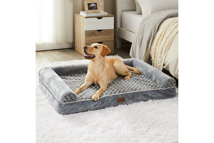 yellow lab dog laying down on a gray dog bed on top of a white rug in a bedroom