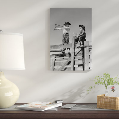 «1950s Two Young Boy Dressed as Cowboys Shoot Slingshots on Top of Wooden Fence Outdoor», reproduction de photo sur toile tendue