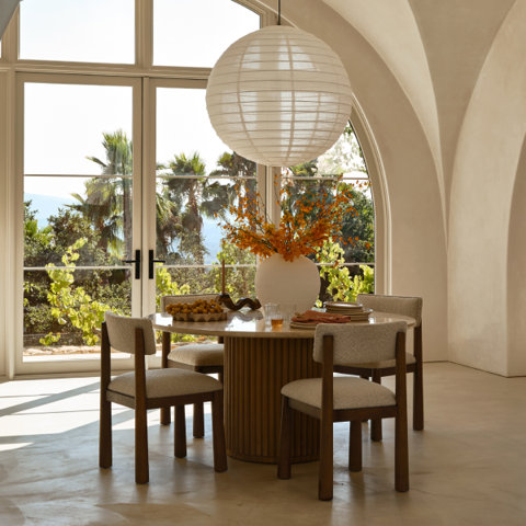 Round dining table and four chairs under paper lantern.