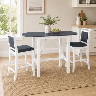 Table compacte à trois tablettes en bois blanc à hauteur de comptoir jumelée à deux chaises de salle à manger rembourrées pour un usage domestique
