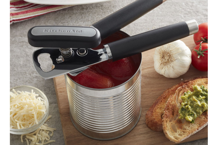 tinned tomatoes with a can opener on top. avocado toast, a head or garlic, and bowl of shredded cheese