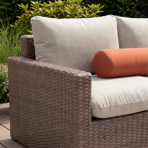 Outdoor seating area with off-white couch, concrete coffee table, and garden backdrop.