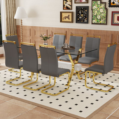 Ensemble de table et de chaises. Ensemble de salle à manger élégant en verre trempé transparent - 71 po x 35,4 po avec 8 chaises en polyuréthane gris clair et pieds en C en tube d'or.