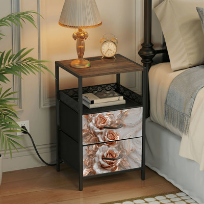 Table de chevet avec station de recharge intégrée, 2 tiroirs, ports USB et prises électriques, tablette ouverte, noire, motif floral rose et marbre.