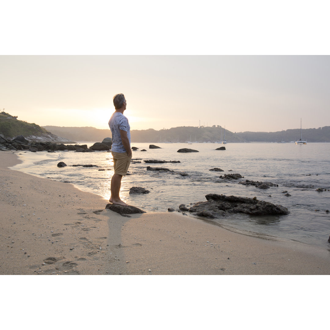 Mann erkundet Strand bei Sonnenaufgang