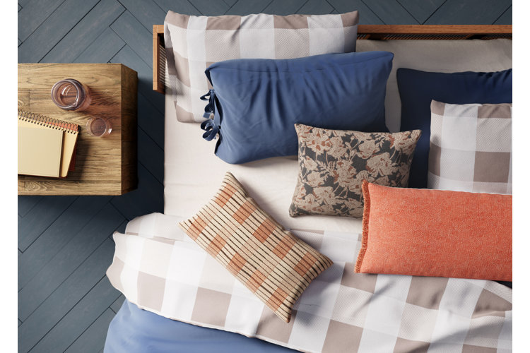 wood bed with light gray gingham sheets, dark blue duvet, and patterned throw pillows