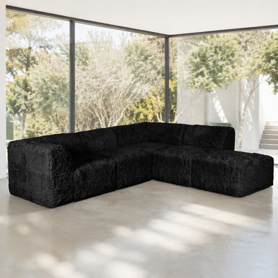 Ensemble de salon modulaire 7 pièces en L, couleur noire, garni de fausse fourrure et de mousse haute densité compressée, avec fauteuils sans accoudoirs et poufs.