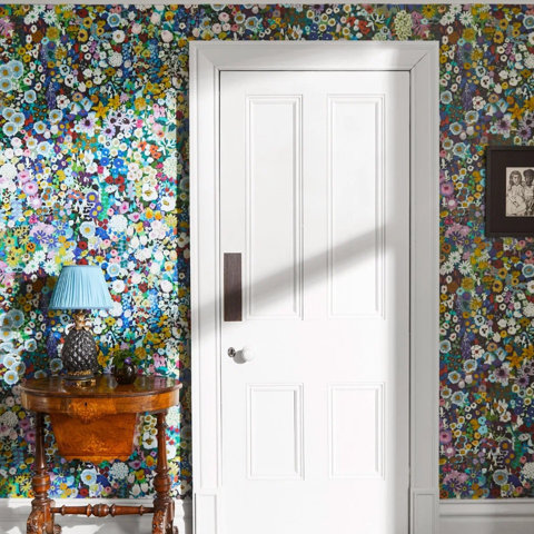Floral wallpaper with white door and accent table.