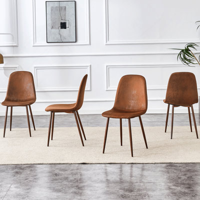 Ensemble de quatre chaises exquises avec dossier en suède et pieds de transfert, parfaites pour rehausser la décoration intérieure dans divers styles