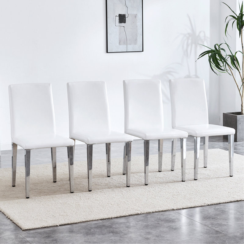 Un ensemble de 4 chaises à dossier en cuir de polyuréthane blanc avec des pieds en métal argenté - la combinaison parfaite, convenant aux styles de maison minimalistes et modernes, avec des dimensions de produit de 16,2 x 18,5 x 34,6 pouces.