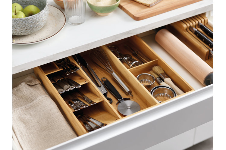 open kitchen drawer with napkins, knives, and flatware in a bamboo organizer
