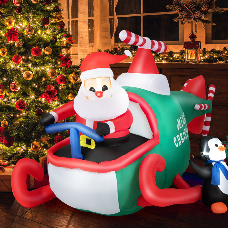 Père Noël conduisant un hélicoptère et un pingouin tenant un cadeau gonflable