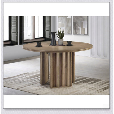 Table de salle à manger ronde d'aspect vieilli avec rallonge intégrée et chaises rembourrées pour des réceptions modernes et polyvalentes à la maison.