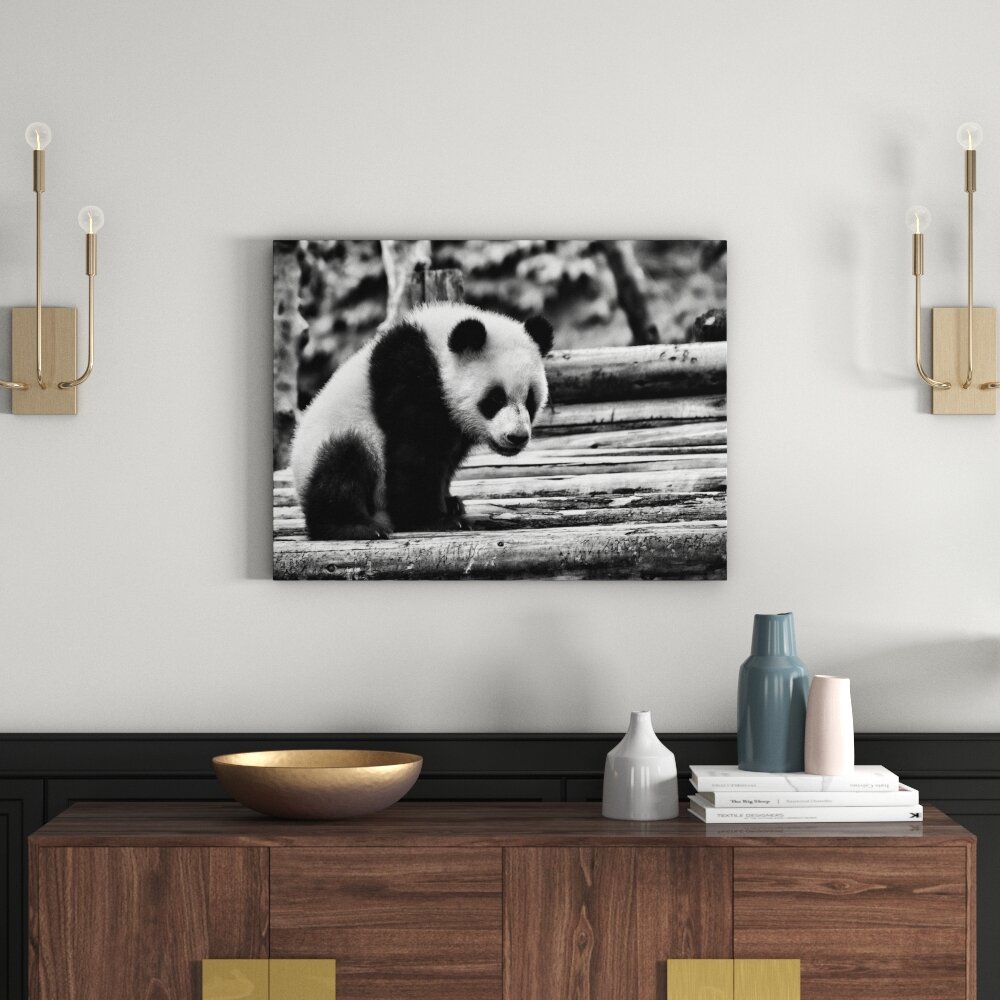 Leinwandbild Niedlicher junger Panda auf Holzstämmen in Monochrom