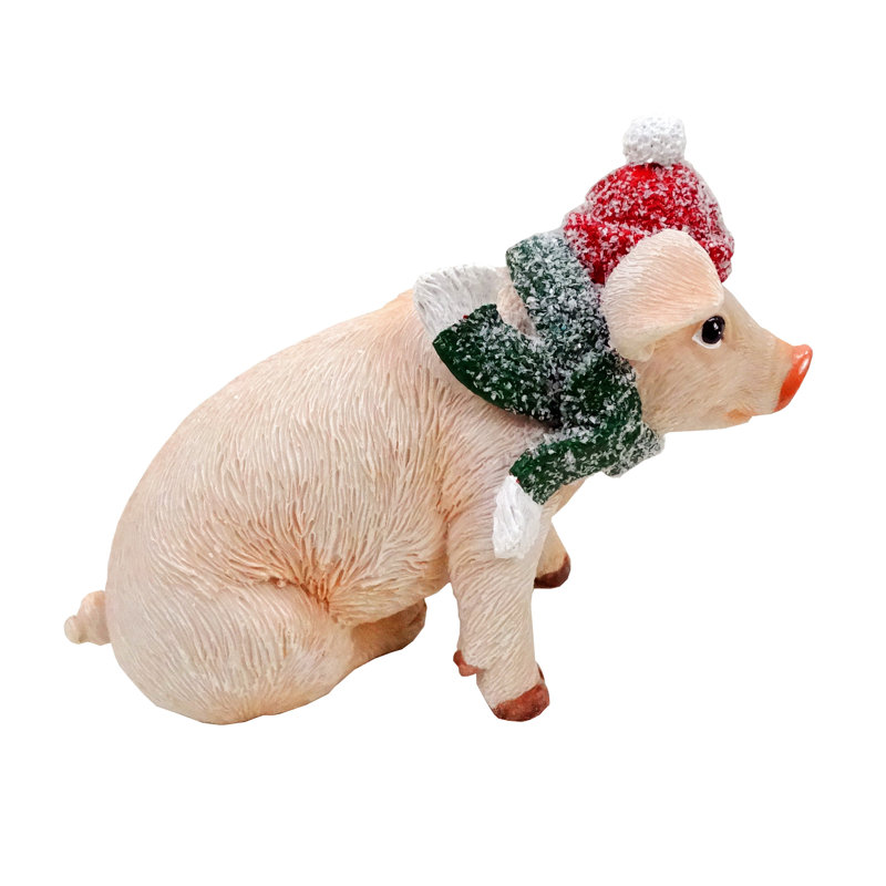 Statue de cochon avec foulard vert et bonnet de neige