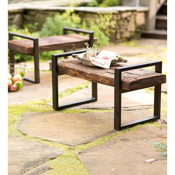 Outdoor garden bench set in a stone patio with a small wooden tray and fruit.
