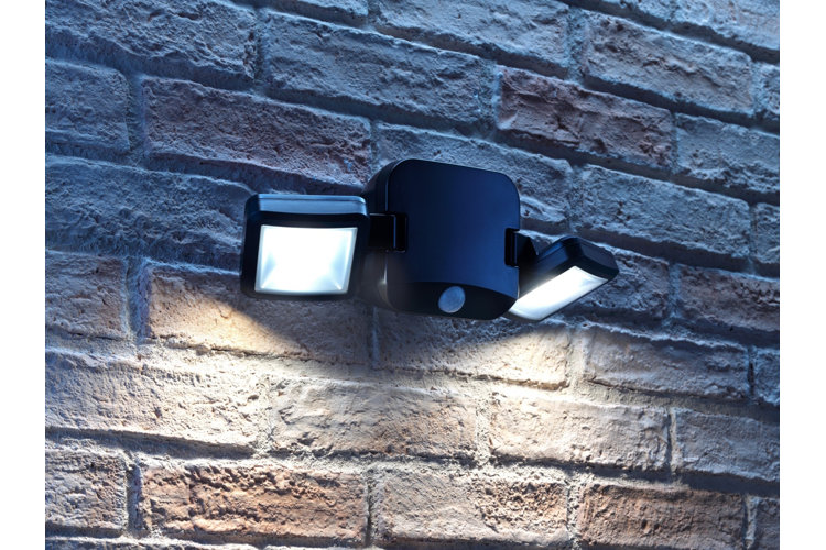 a two-light spotlight with a motion sensor on the side of a home