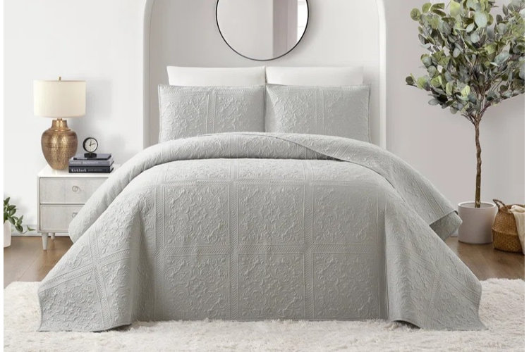 transitional-style bedroom with white walls, an arched alcove, a white shag area rug, and a gray ornate bedspread and pillow shams