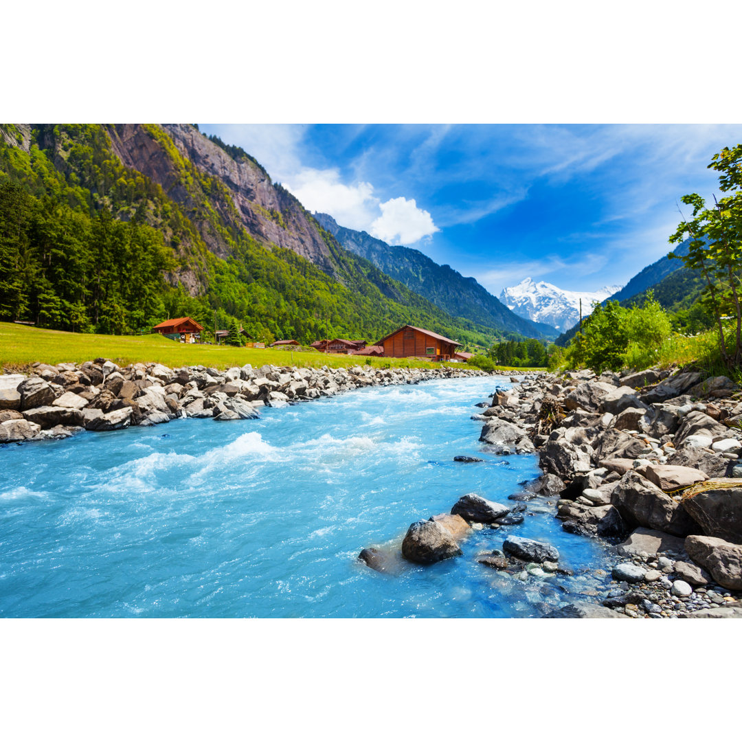 Leinwandbild Schweizer Landschaft mit Flusslauf und Häusern