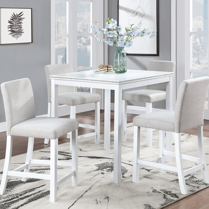 Ensemble table et chaises de salle à manger blanches, hauteur du comptoir, forme carrée avec broderie de cristal. Structure en bois massif. Quatre chaises blanches rembourrées.