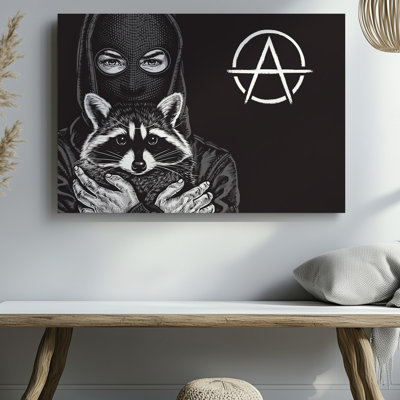 "Toile", une figure enveloppée dans un masque noir texturé et un capuchon d'art domine l'avant-plan berçant un raton laveur