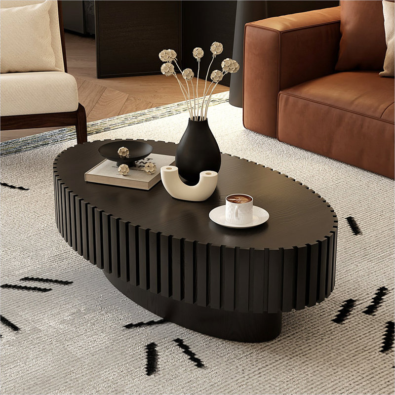 Table basse avec détails en relief artisanaux, piédestal ovale noir profond pour le salon