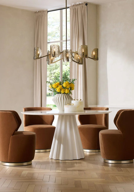 Dining room with brown chairs, round white table, and modern chandelier.