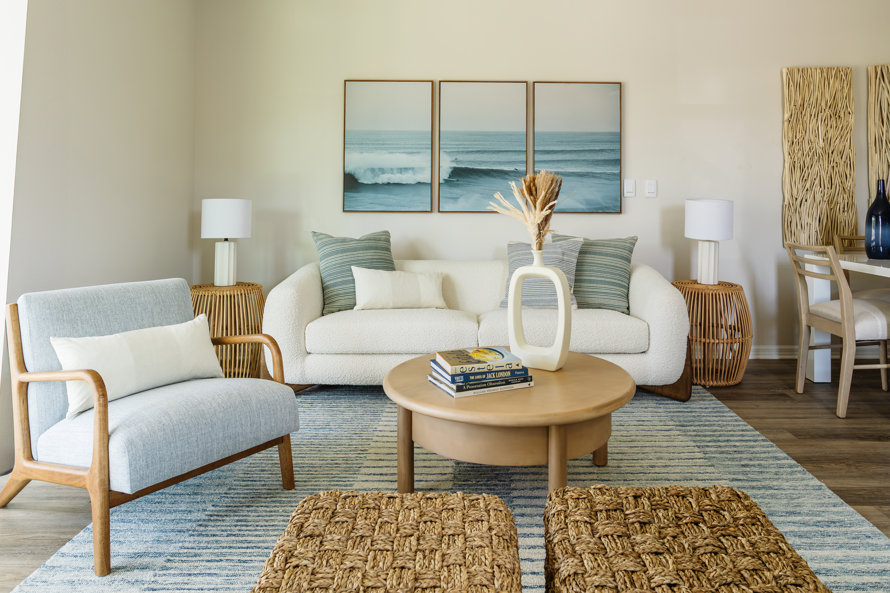 Coastal living room decor with sofa, chair, and round coffee table with books: Viotte, The Lives of Jack London, A Possession Obsession, and William Wegman Paintings.