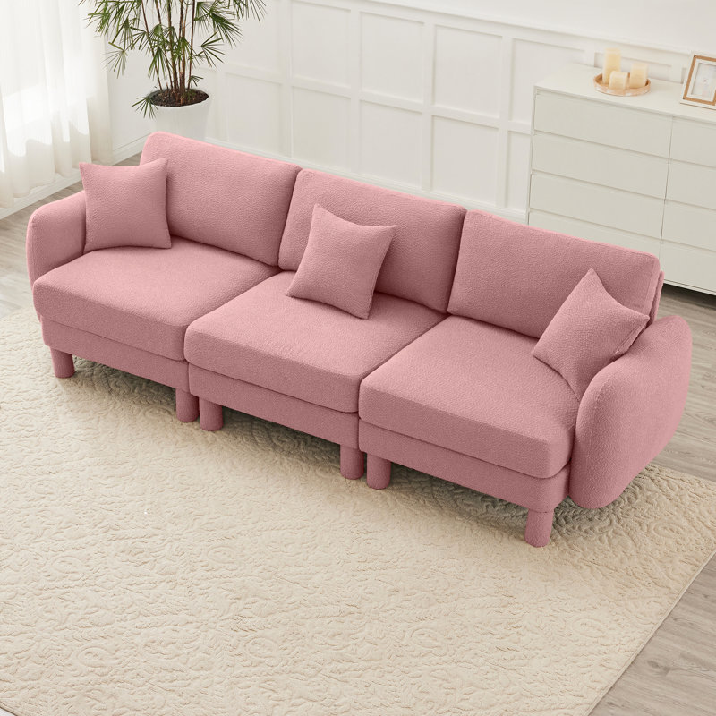 Canapé 3 places en tissu rose avec des pieds cylindriques et distinctifs, confortable pour les séances de lecture