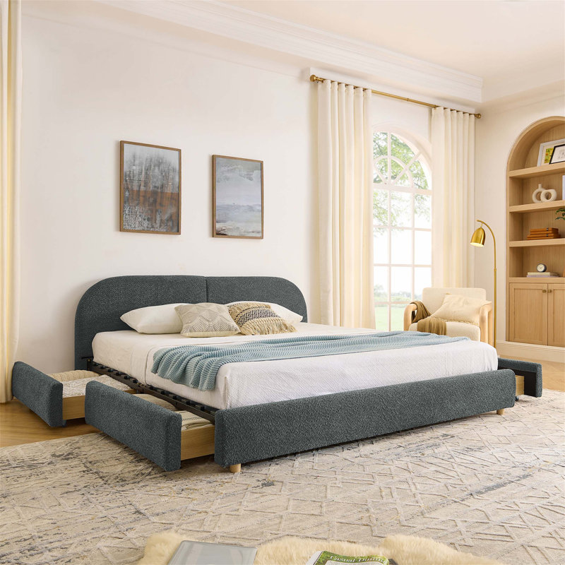 Structure de lit rembourrée avec tête de lit courbée et quatre tiroirs de rangement à roulettes pour matelas très grand.