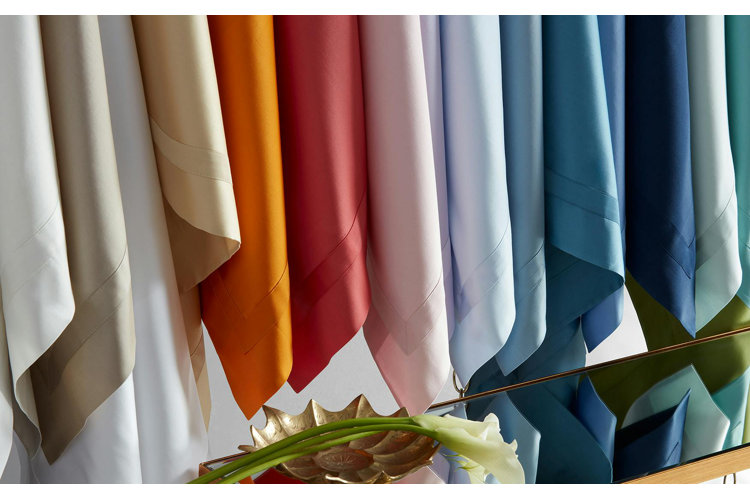 an array of different colored bed sheets all hanging up