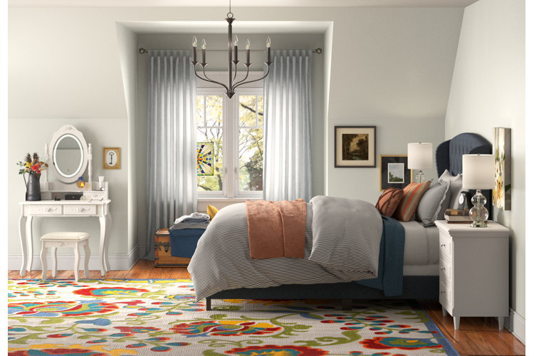 Traditional bedroom with an area rug that features primary colors, a navy blue bed, and a white bedroom vanity.