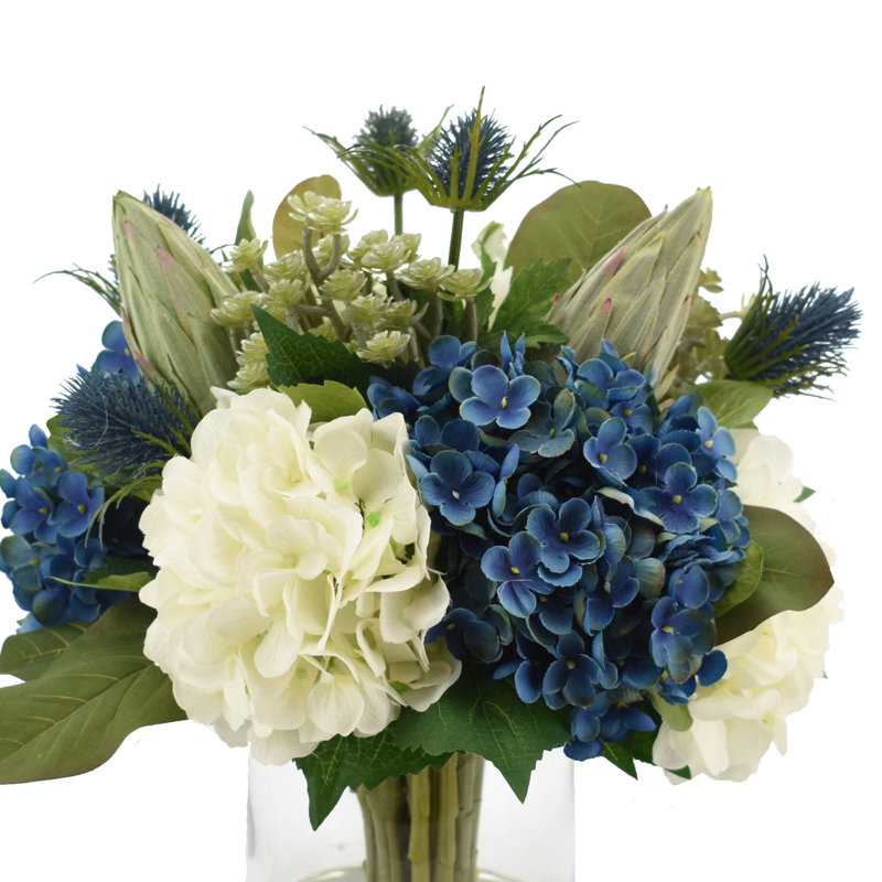 Assortiment d'hortensias avec chardon, cactus et protées dans un vase en verre Allan