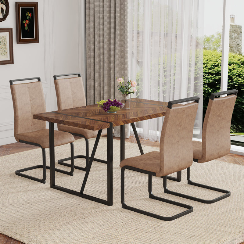 Ensemble de table et de chaises. Une table de salle à manger rectangulaire rétro avec un bureau en panneau de fibres à densité moyenne à motif en arête de poisson et des pieds en métal noir. Assorti de 4 chaises en tissu brun avec des pieds arqués noirs.
