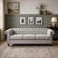 Canapé 3 places de style Chesterfield avec capitonnage à boutons, clous décoratifs et accoudoirs sculptés pour des espaces de vie élégants.