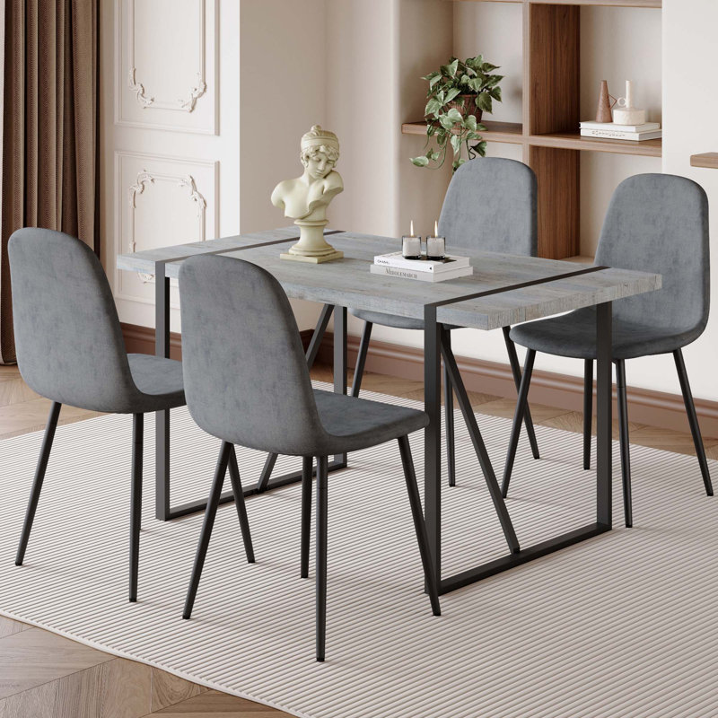 Une table de salle à manger rectangulaire rétro minimaliste avec un dessus spécialement texturé et des pieds en métal, jumelés à 4 chaises