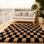 Black and camel-colored checkered area rug for indoor use, suitable for living rooms, bedrooms, and children's rooms.