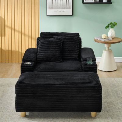Canapé simple en velours côtelé noir avec un coussin, deux coussins décoratifs, un repose-pieds et deux espaces de rangement.