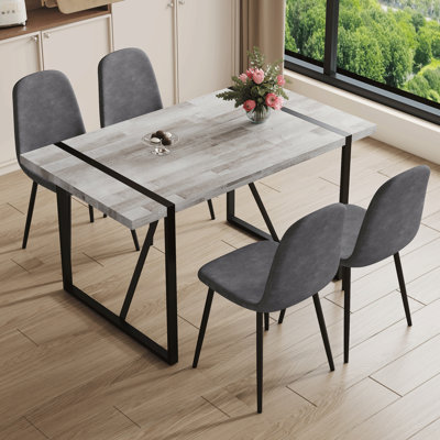 Ensemble de table et de chaises. Une table de salle à manger rectangulaire rétro minimaliste avec un dessus spécialement texturé et des pieds en métal noir. Assorti de 4 chaises en tissu de lin gris foncé.