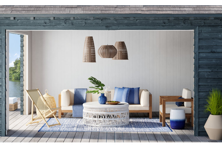 coastal sitting room with a teak patio set, dark blue rug, and matching blue throw pillows
