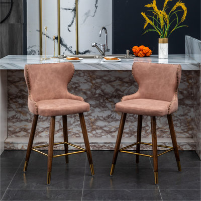 2 tabourets de comptoir Mid-Century modernes roses - similicuir, détails cloutés, siège incurvé, pieds en bois de noyer, repose-pieds en métal doré, 2 tabourets en cuir avec garniture, tissu d'ameublement en suède, or effilé