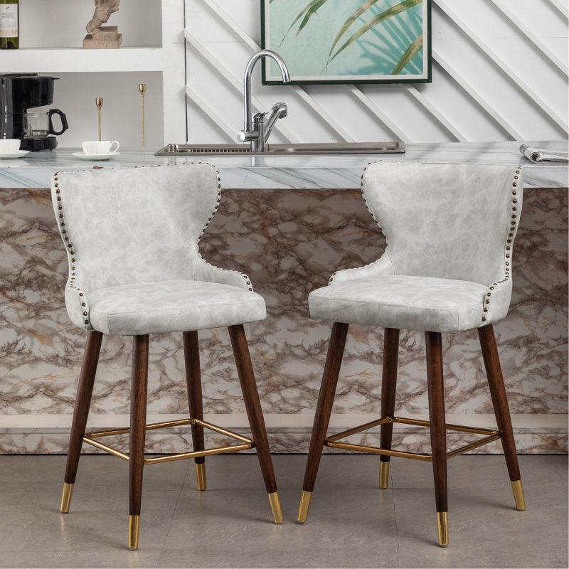 2 tabourets de comptoir modernes de style Mid-Century, siège en similicuir, dossier capitonné, repose-pieds incurvé doré, siège avec garniture cloutée, pieds en bois massif