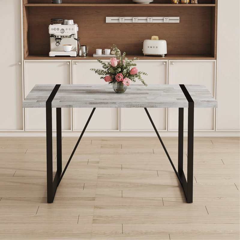 Une table de salle à manger rectangulaire rétro minimaliste avec un dessus spécialement texturé et des pieds en métal noir. Plateau de table contemporain en panneau de fibres à densité moyenne gris minimaliste.