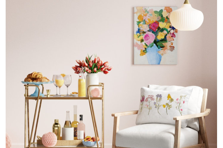 A bar cart with a blue cake stand used to display croissants beside a tulip arrangement and next to a white accent chair.