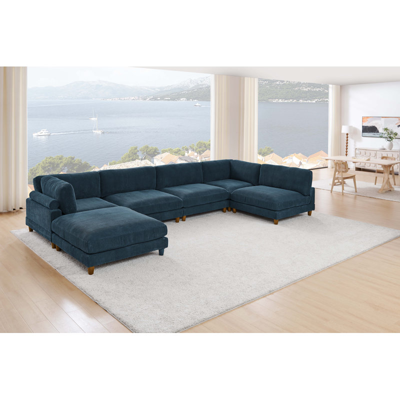 Large navy sectional sofa in a bright and spacious living room with a stunning sea view and minimalist decor.