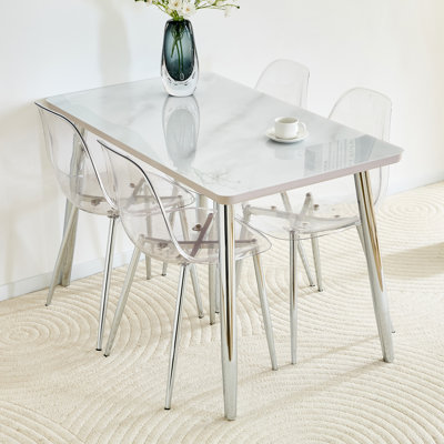 Ensemble de table et de chaises avec plateau en verre imitation marbre blanc, base en panneau de fibres à densité moyenne, pieds fuselés en métal argenté et 4 chaises en plastique transparent avec pieds en métal argenté