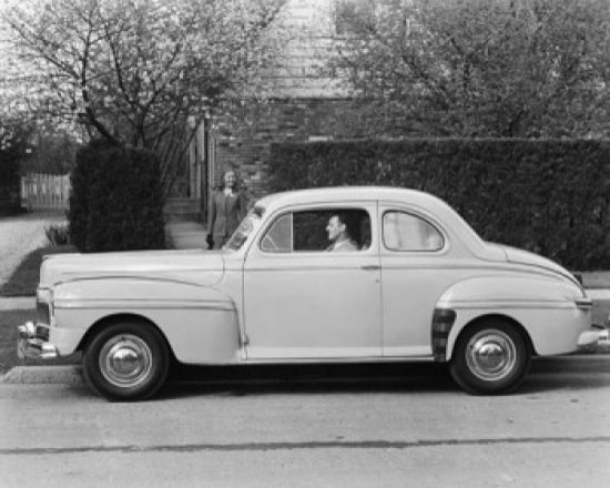 «Man Sitting In A Mercury Sedan Coupe 1946» avec une femme debout à ses côtés
