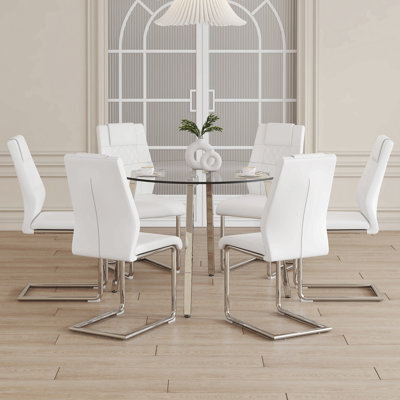 Ensemble de table et de chaises. Une table ronde en verre trempé transparent de style minimaliste moderne avec des pieds en métal argenté. Assorti aux chaises en cuir synthétique moderne à dossier haut et aux pieds chromés en forme de C