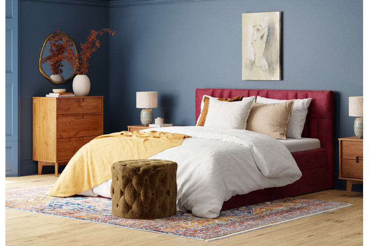 transitional-style bedroom with blue walls, burgundy upholstered bed, and an Oriental rug