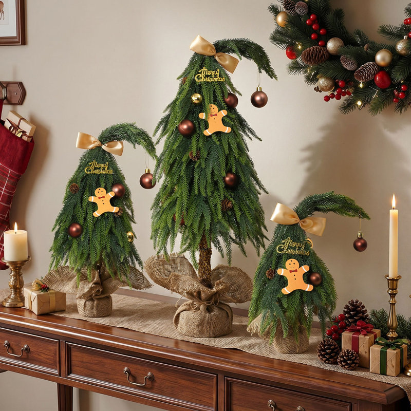 Sapins de Noël fantaisie en 3 parties, à cime incurvée, ornés de décorations dorées, de motifs en pain d'épice et de bases en toile de jute